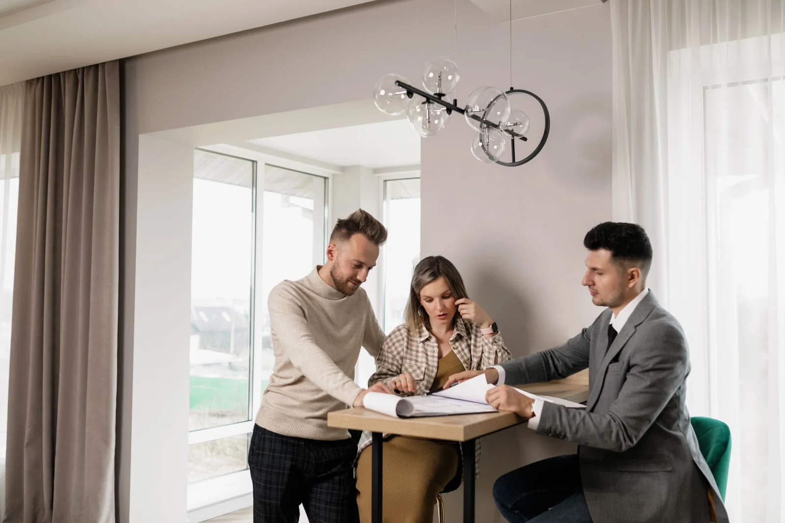 Couple signant une offre d'achat immobilier à une table avec un stylo et un dossier